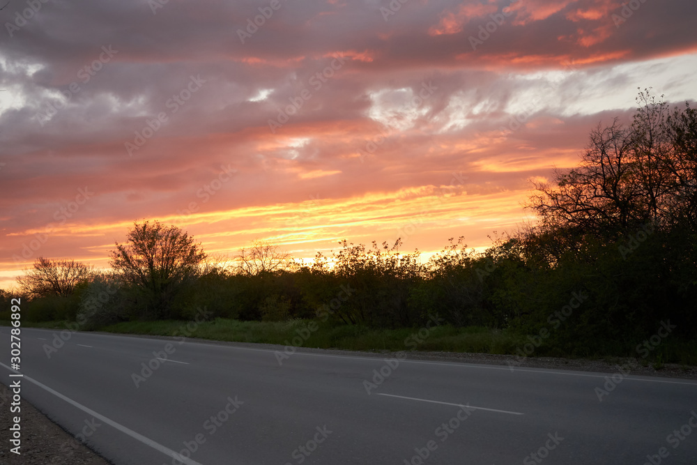 Empty asphalt road on a fantastic orange sunset background