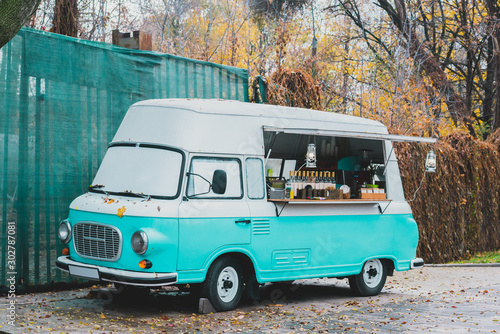 Turquoise and white street food retro van in the autumn's park sells coffee. Business. Work. Outdoor. Entrepreneur. Mobile coffee truck photo