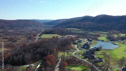 aerial view at Scenic Overlook, the drone pans right towards a golf club. It's a sunny day, with fall foliage on the mountains, a lake, the golf course, open fields & treetops below in Amenia, NY photo