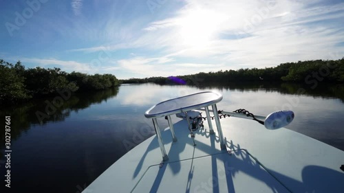 Dramatic POV, boat speeding through remote, calm, twisty creek toward sun