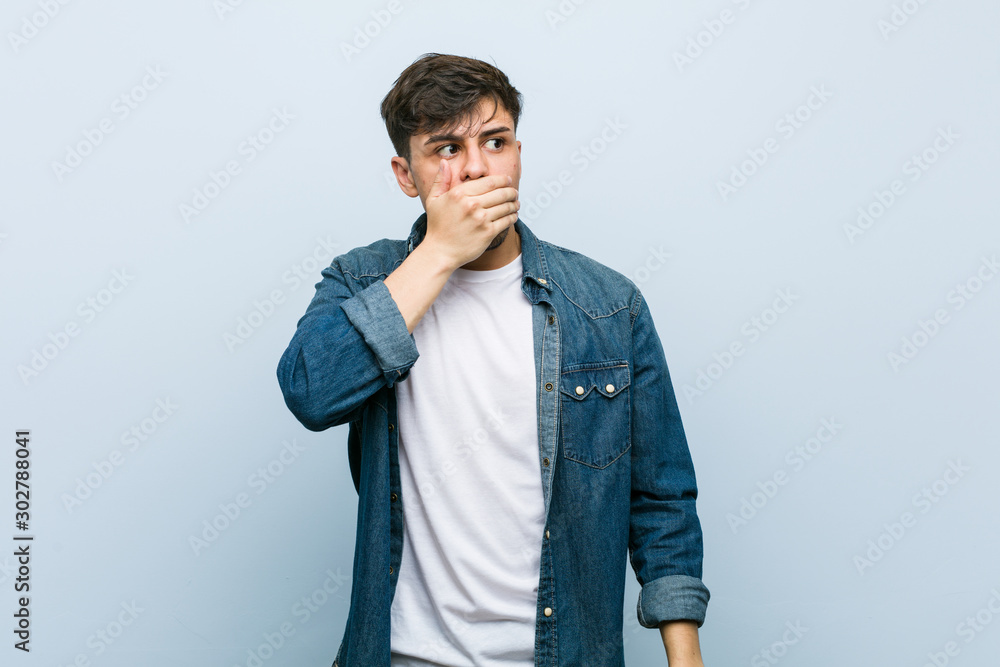 Young hispanic cool man thoughtful looking to a copy space covering mouth with hand. Young hispanic cool man thoughtful looking to a copy space covering mouth with hand.