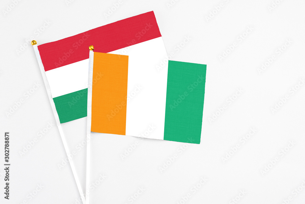 Cote D'Ivoire and Hungary stick flags on white background. High quality fabric, miniature national flag. Peaceful global concept.White floor for copy space. Cote D'Ivoire and Hungary stick flags on white background. High quality fabric, miniature national flag. Peaceful global concept.White floor for copy space.
