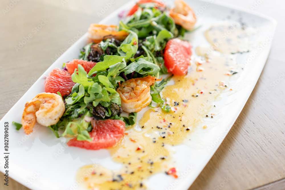 Delicious dish with grilled shrimps, slice grapefruit and arugula salad and spicy fried prawns. Restaurant menu, natural and organic food concept. Delicious dish with grilled shrimps, slice grapefruit and arugula salad and spicy fried prawns. Restaurant menu, natural and organic food concept.