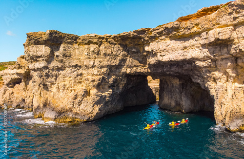 Group of kayakers under cave. Comino island. Drone landscape. Europe. Maltese islands 