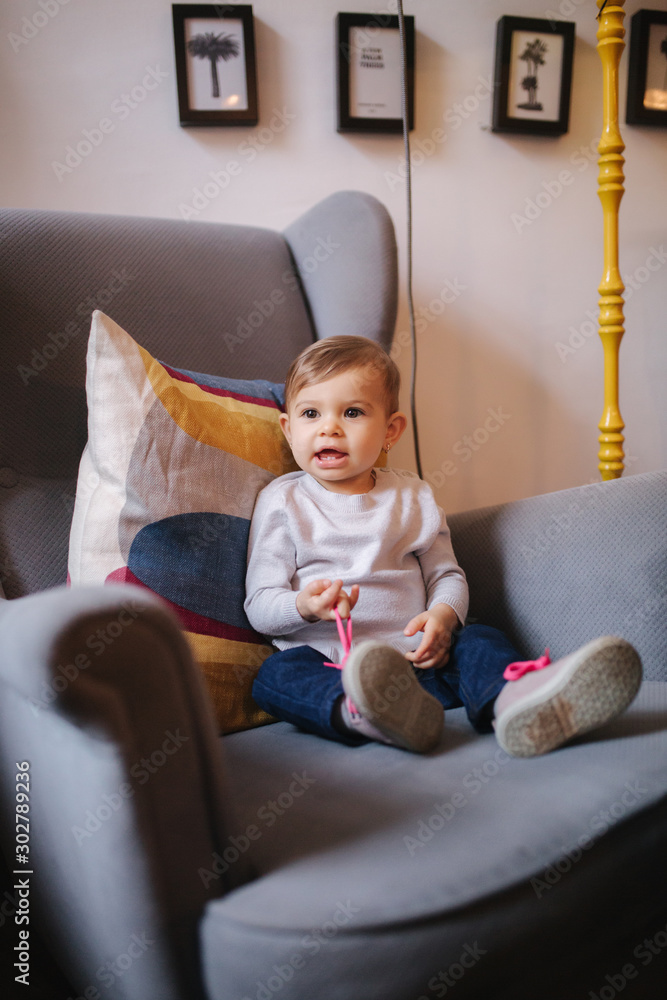 Fototapeta premium Cute baby girl sitting on big armchair and smile