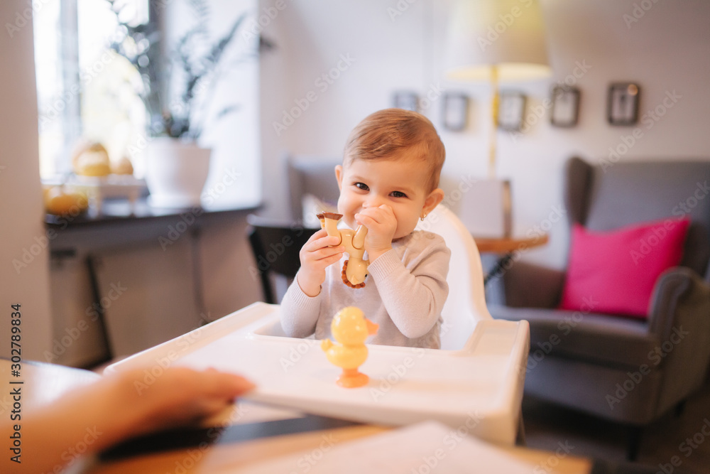 Cute baby girl sitting on highchair in cafe and play with toy Cute baby girl sitting on highchair in cafe and play with toy