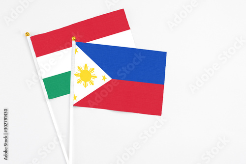 Philippines and Hungary stick flags on white background. High quality fabric  miniature national flag. Peaceful global concept.White floor for copy space.
