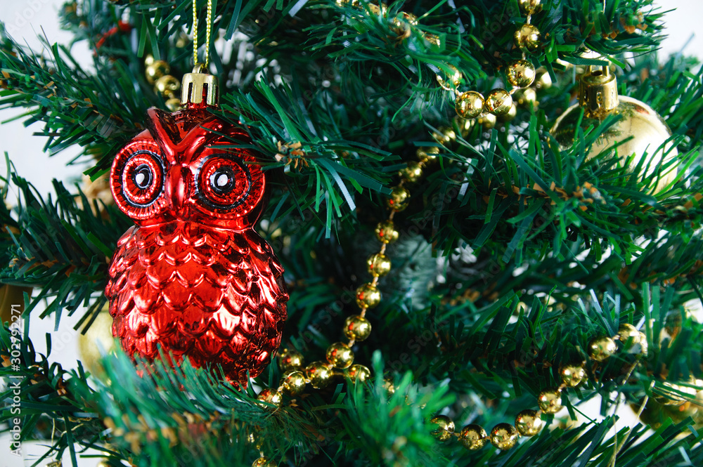 Christmas glass decoration owl on the background of a decorated Christmas tree. Close-up.