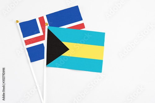 Bahamas and Iceland stick flags on white background. High quality fabric  miniature national flag. Peaceful global concept.White floor for copy space.