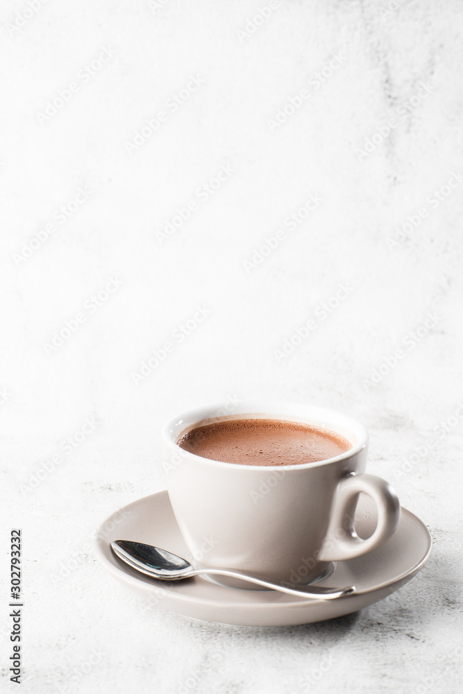 Cup of hot cocoa or hot chocolate or americano in white cup isolated on bright marble background. Overhead view, copy space. Vertical photo. traditional drinks for winter time Cup of hot cocoa or hot chocolate or americano in white cup isolated on bright marble background. Overhead view, copy space. Vertical photo. traditional drinks for winter time