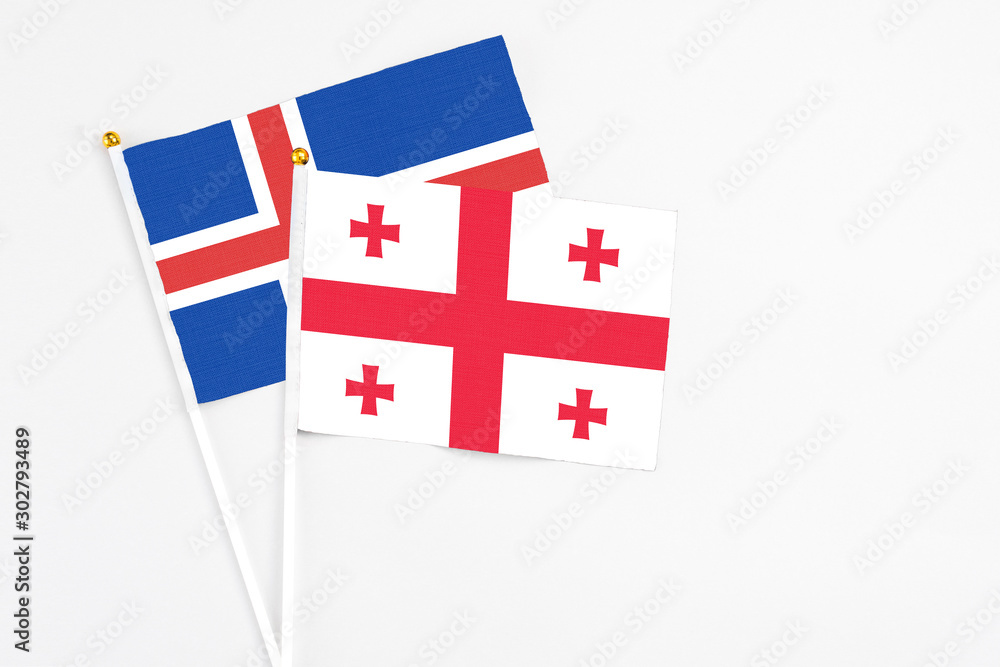 Georgia and Iceland stick flags on white background. High quality fabric, miniature national flag. Peaceful global concept.White floor for copy space.