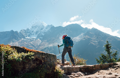 Young hiker backpacker woman using trekking poles enjoying Everest Base Camp trekking route with Thamserku 6608m mountain on background during high altitude Acclimatization walk in Sagarmatha NP,Nepal photo