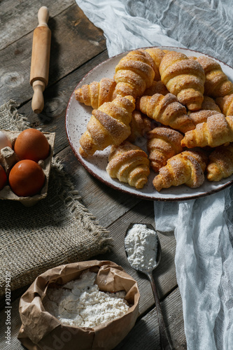 bagels lie in a plate on an old wooden background, next to eggs and flour. bakery products