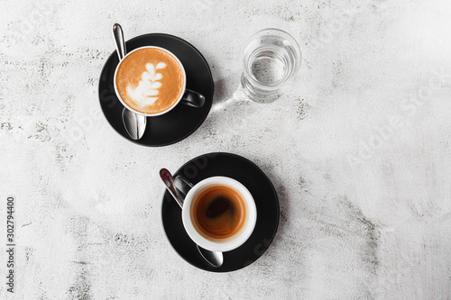 Obraz na płótnie Two dark cups of hot black coffee, espresso, cappuccino with milk isolated on bright marble background. Overhead view, copy space. Advertising for cafe menu. Coffee shop menu. Horizontal photo. w salonie