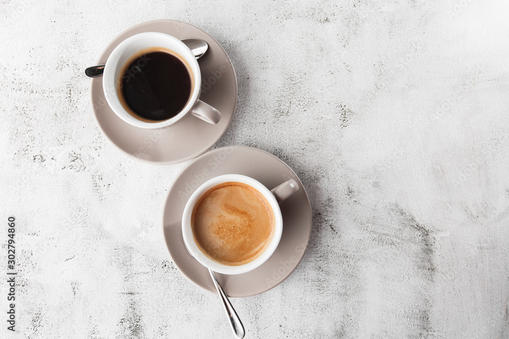 Two white cups of hot black coffee with milk isolated on bright marble background. Overhead view, copy space. Advertising for cafe menu. Coffee shop menu. Horizontal photo.