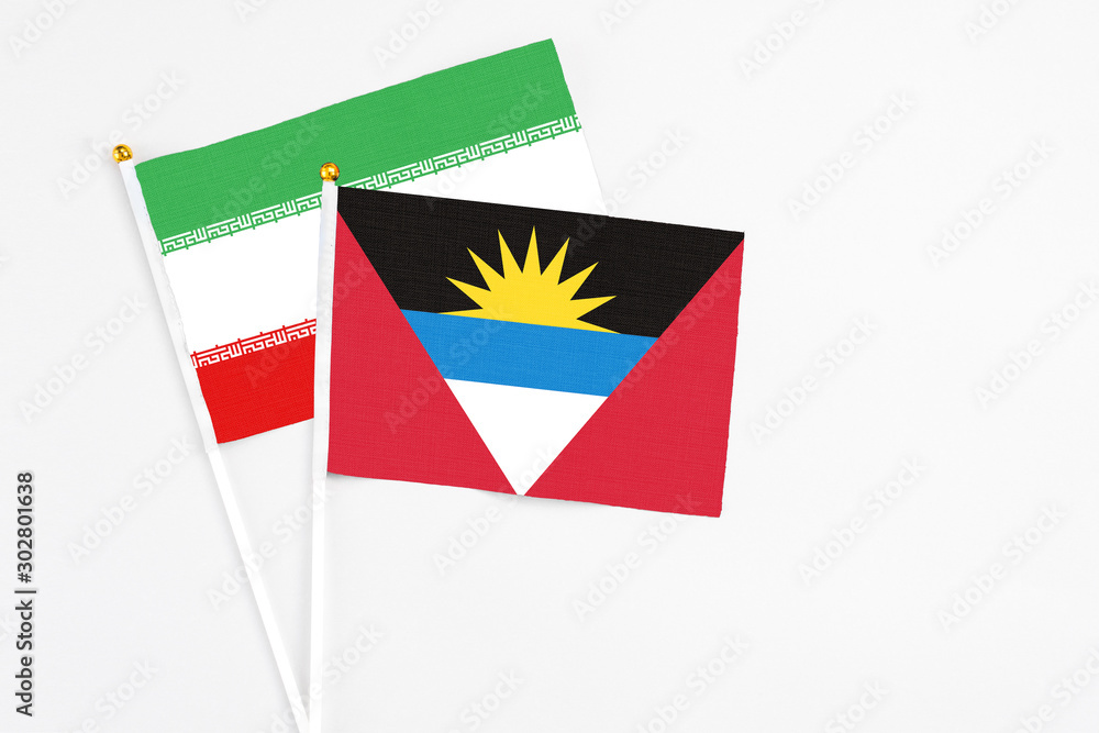 Antigua and Barbuda and Iran stick flags on white background. High quality fabric, miniature national flag. Peaceful global concept.White floor for copy space.
