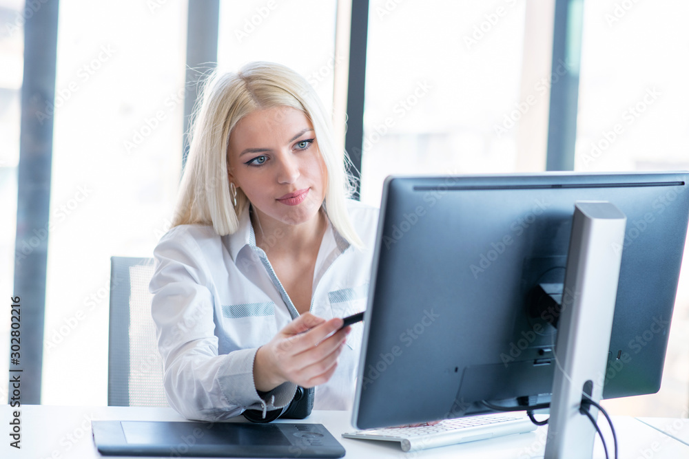 Professional photographer sitting at her office desk looking away and smiling. Professional photographer sitting at her office desk looking away and smiling.
