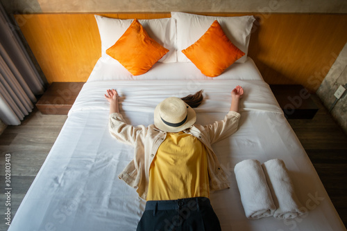 Funny shot of woman sleeping on bed, raised her hands with comfortable cushion bed. Conceptual of woman lifestyle and accomodation.