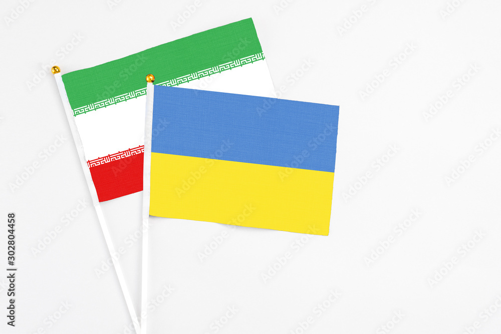 Ukraine and Iran stick flags on white background. High quality fabric, miniature national flag. Peaceful global concept.White floor for copy space. Ukraine and Iran stick flags on white background. High quality fabric, miniature national flag. Peaceful global concept.White floor for copy space.