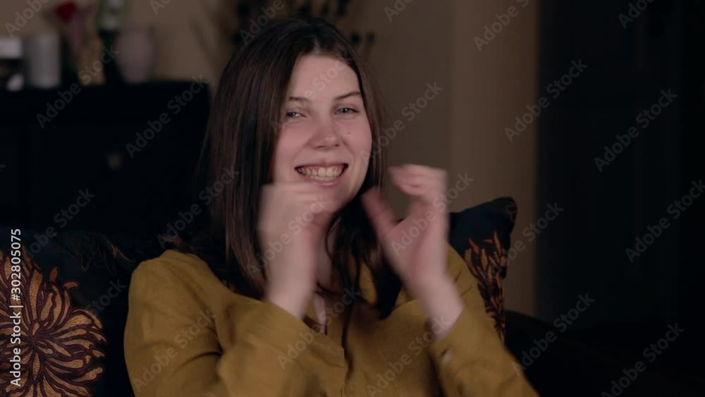 A young pretty woman of Caucasian appearance sits in a chair clapping her hands and rejoices. Successful finale. The task is completed, everything turned out A young pretty woman of Caucasian appearance sits in a chair clapping her hands and rejoices. Successful finale. The task is completed, everything turned out