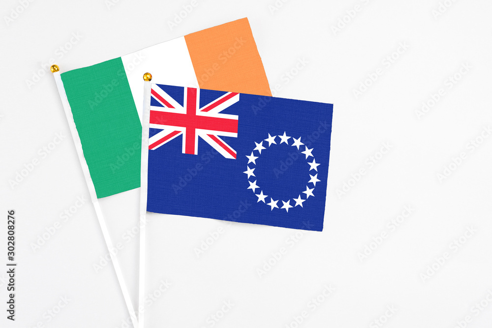 Fototapeta premium Cook Islands and Ireland stick flags on white background. High quality fabric, miniature national flag. Peaceful global concept.White floor for copy space