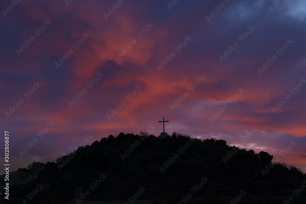 pink and purple skies illuminate hilltop cross