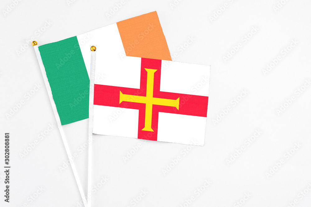 Guernsey and Ireland stick flags on white background. High quality fabric, miniature national flag. Peaceful global concept.White floor for copy space