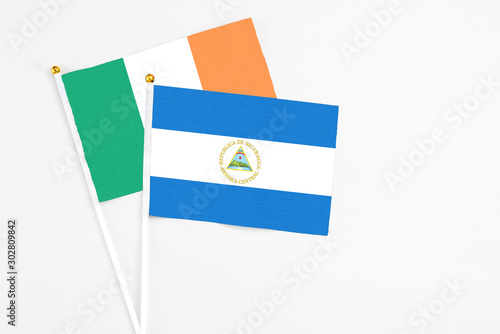 Nicaragua and Ireland stick flags on white background. High quality fabric, miniature national flag. Peaceful global concept.White floor for copy space photo