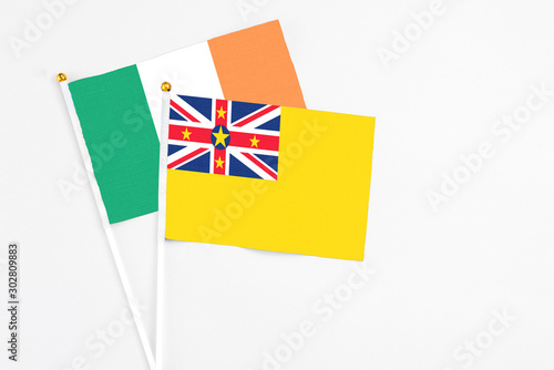 Niue and Ireland stick flags on white background. High quality fabric, miniature national flag. Peaceful global concept.White floor for copy space photo