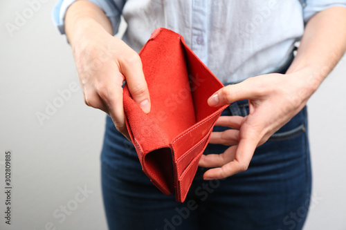 Woman showing empty wallet on light background, closeup