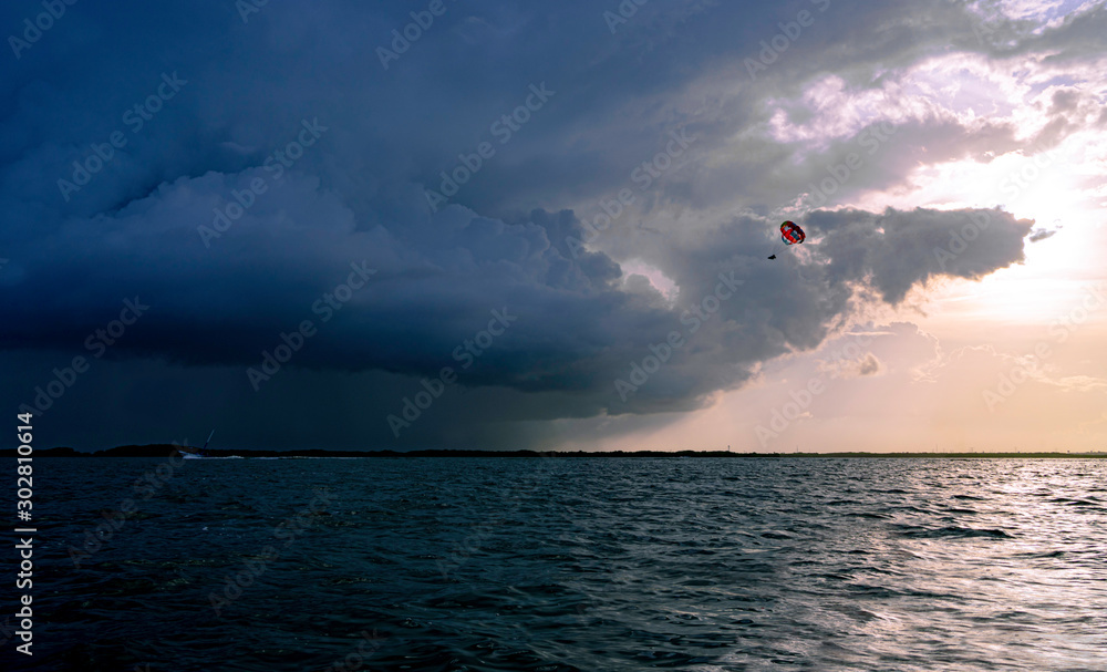 Parasailing into the stormy cloud during sunset hour.