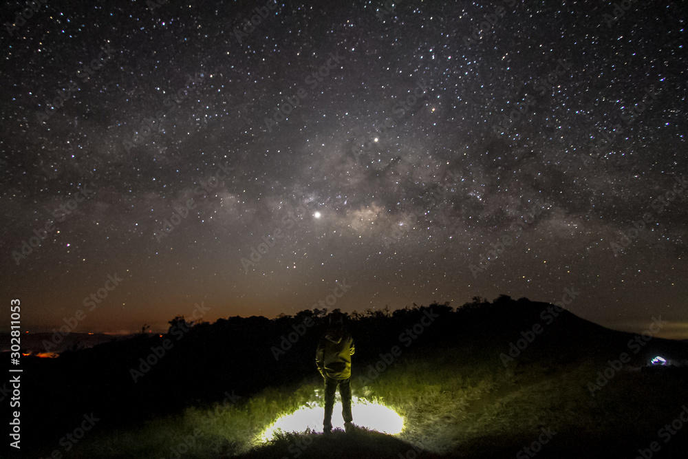 milky way in night sky over mountain with man in background