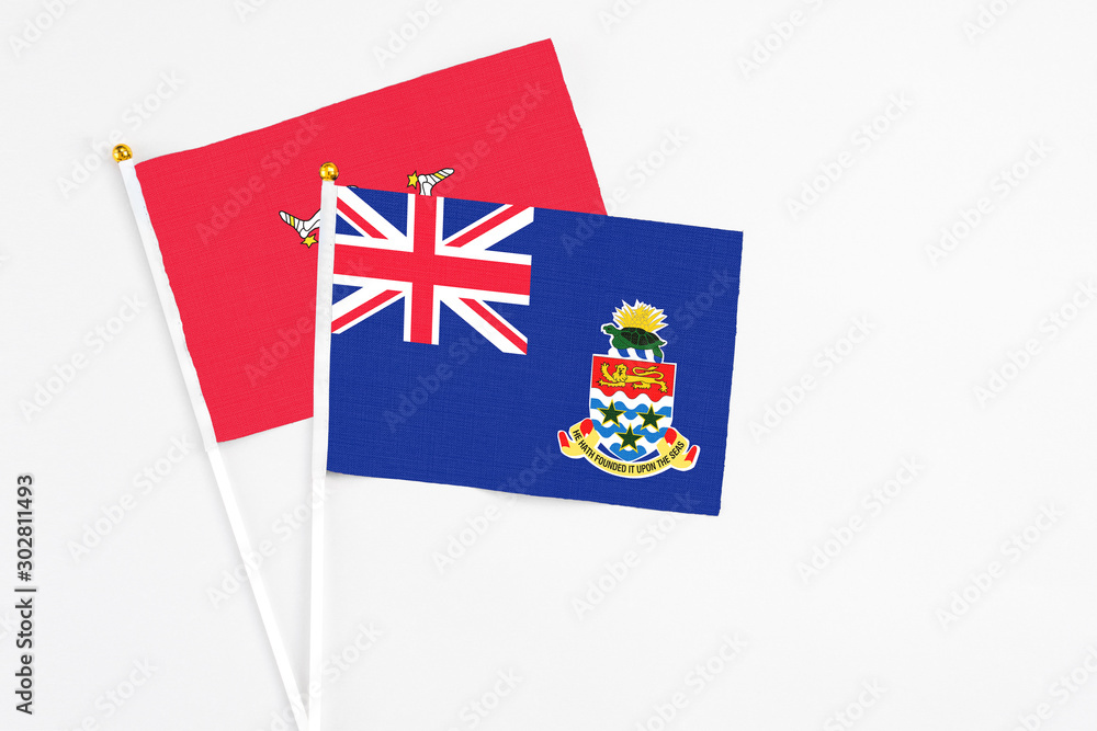 Fototapeta premium Cayman Islands and Isle Of Man stick flags on white background. High quality fabric, miniature national flag. Peaceful global concept.White floor for copy space.