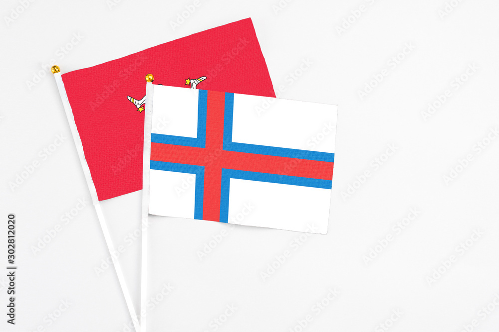 Faroe Islands and Isle Of Man stick flags on white background. High quality fabric, miniature national flag. Peaceful global concept.White floor for copy space.