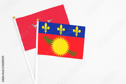 Guadeloupe and Isle Of Man stick flags on white background. High quality fabric, miniature national flag. Peaceful global concept.White floor for copy space.