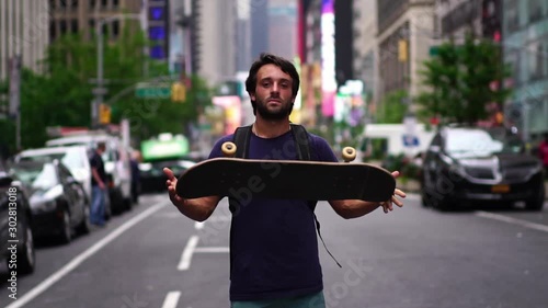 Portrait of confident millennial new yorker. Skateboarder guy holding skateboard. Concept of urban healthy active lifestyle, adventure, american youth, hipster in NYC.