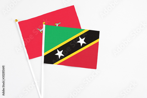 Saint Kitts And Nevis and Isle Of Man stick flags on white background. High quality fabric, miniature national flag. Peaceful global concept.White floor for copy space.