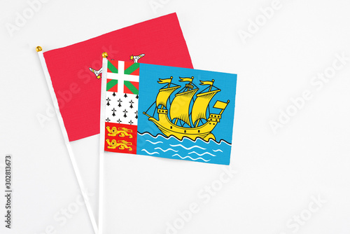 Saint Pierre And Miquelon and Isle Of Man stick flags on white background. High quality fabric, miniature national flag. Peaceful global concept.White floor for copy space.
