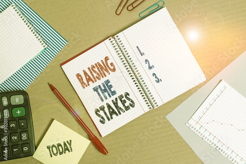 Handwriting text Raising The Stakes. Conceptual photo Increase the Bid or Value Outdo current bet or risk Striped paperboard notebook cardboard office study supplies chart paper photo