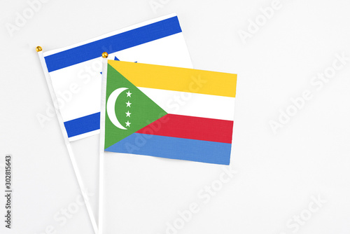 Comoros and Israel stick flags on white background. High quality fabric  miniature national flag. Peaceful global concept.White floor for copy space.