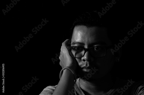 Asian men wear glasses in the dark to look sad. He is thinking something Look at the symptoms of depression.