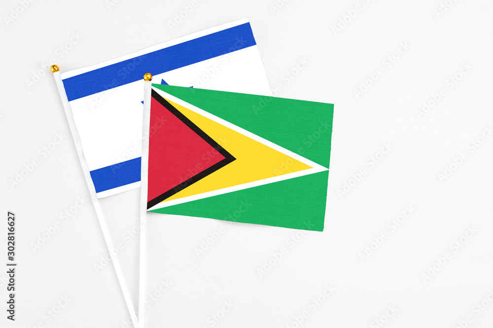 Fototapeta premium Guyana and Israel stick flags on white background. High quality fabric, miniature national flag. Peaceful global concept.White floor for copy space.