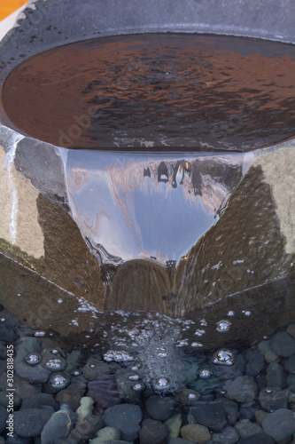 waterfall fountain out of circluar rock close photo