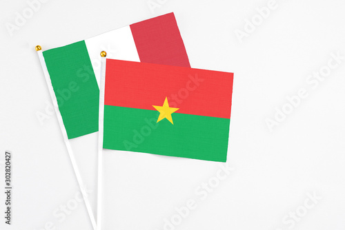 Burkina Faso and Italy stick flags on white background. High quality fabric, miniature national flag. Peaceful global concept.White floor for copy space.