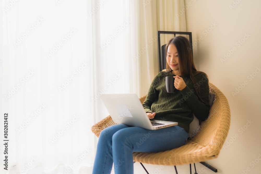 Portrait beautiful young asian women using computer or laptop for working and sitting on sofa chair Portrait beautiful young asian women using computer or laptop for working and sitting on sofa chair