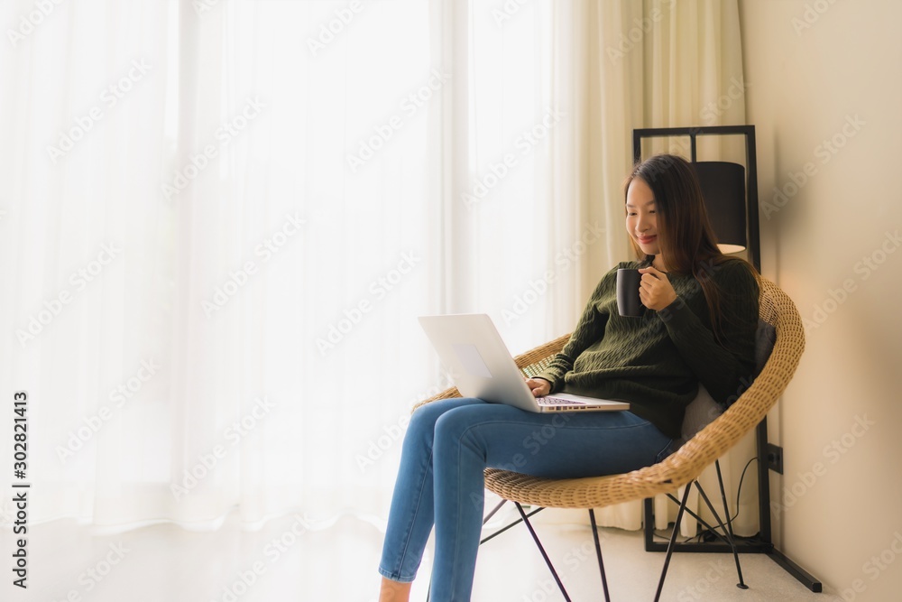 Portrait beautiful young asian women using computer or laptop for working and sitting on sofa chair Portrait beautiful young asian women using computer or laptop for working and sitting on sofa chair
