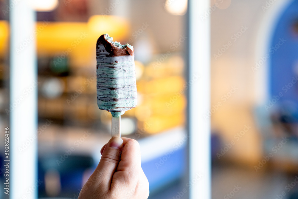 Hand holding green chocolate ice cream sticks with bokeh blur background Hand holding green chocolate ice cream sticks with bokeh blur background