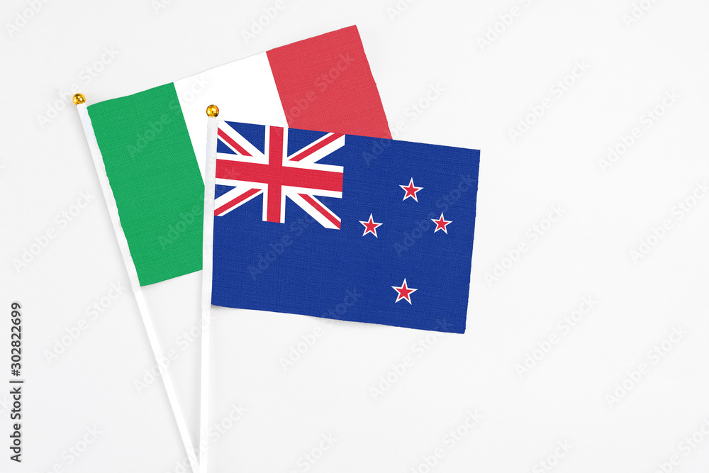 Fototapeta premium New Zealand and Italy stick flags on white background. High quality fabric, miniature national flag. Peaceful global concept.White floor for copy space.