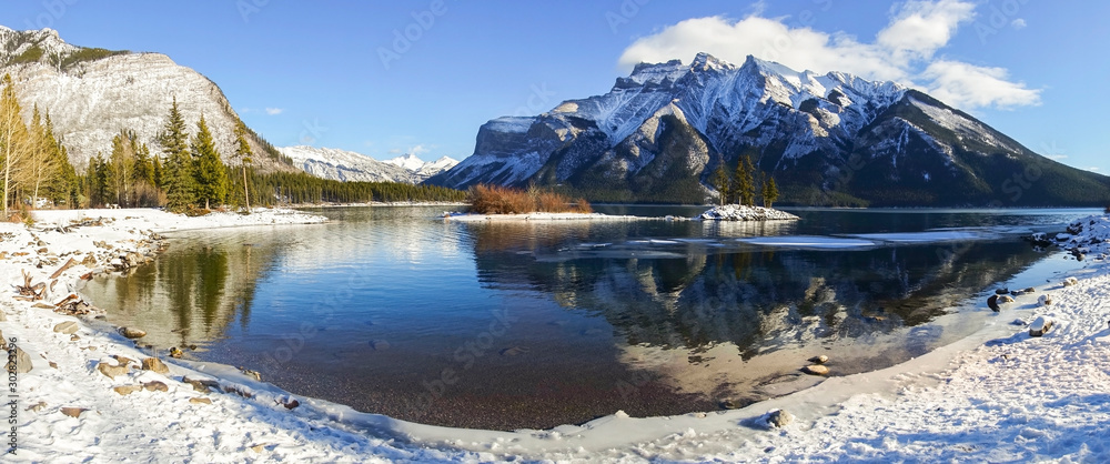 Wide Panoramic Landscape Scenery of Lake Minnewanka With Low Clouds on Snowcapped Mountain Peaks in Banff National Park, Alberta, Canadian Rockies