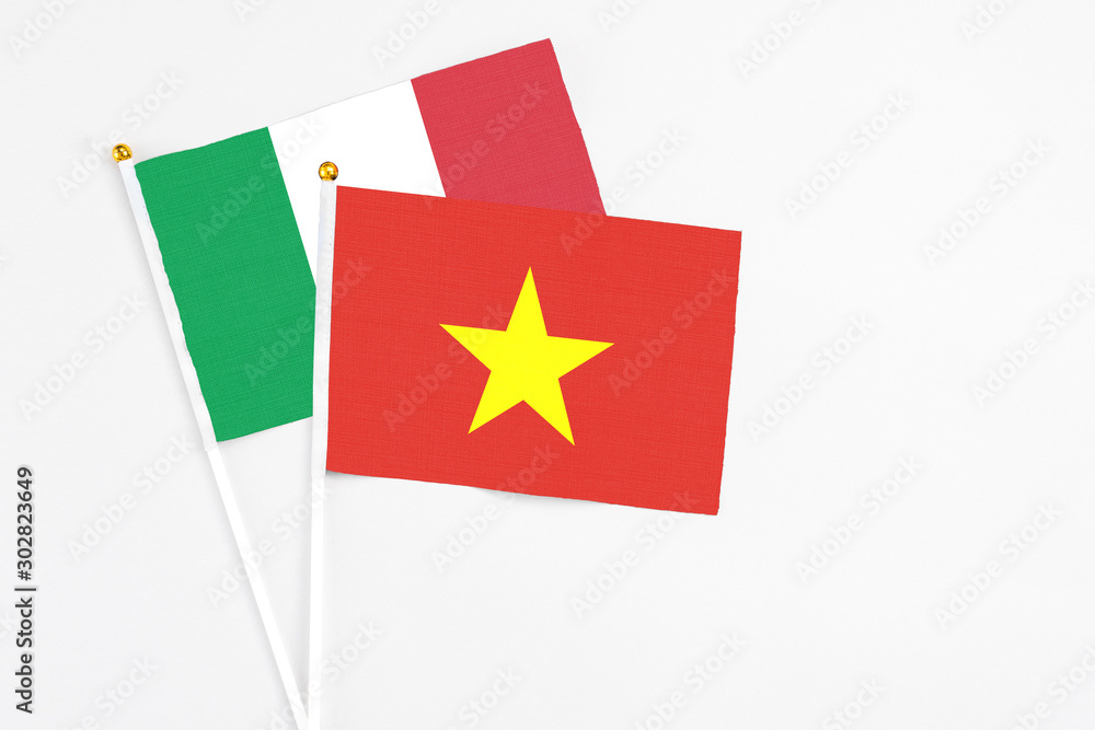 Vietnam and Italy stick flags on white background. High quality fabric, miniature national flag. Peaceful global concept.White floor for copy space. Vietnam and Italy stick flags on white background. High quality fabric, miniature national flag. Peaceful global concept.White floor for copy space.